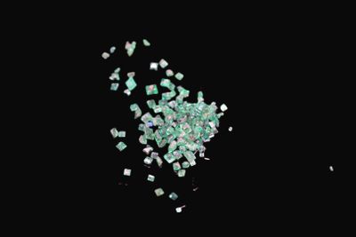 some pieces of green glass are scattered on a black surface