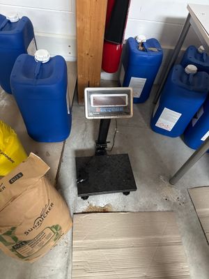 a scale on the floor next to some blue barrels