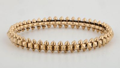 a close up of a gold bracelet with spikes on it