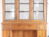 a wooden china cabinet with glass doors in a room