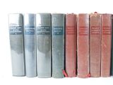 several old books are lined up on a shelf in a row