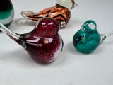 three glass birds sitting next to each other on a white surface