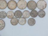 a lot of old silver coins on a white surface