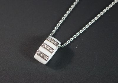 un gros plan d'un collier posé sur une surface noire, avec une chaîne