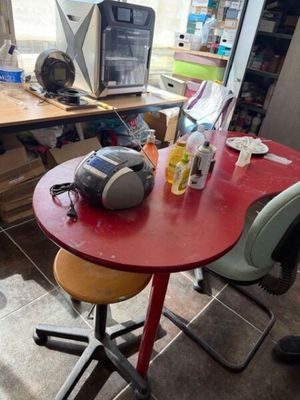 une table rouge sur laquelle se trouvent deux chaises et un micro-ondes