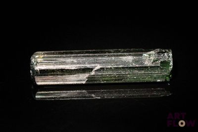 un gros plan d'un cristal vert et blanc sur une surface noire