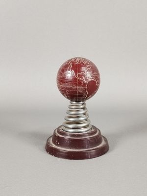 une boule de marbre rouge posée sur un socle en métal