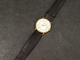 an image of a watch on a black surface with a black strap