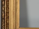 an image of a gold framed mirror on a wooden table