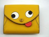 un gros plan sur un petit portefeuille jaune avec des yeux et une langue qui en sort