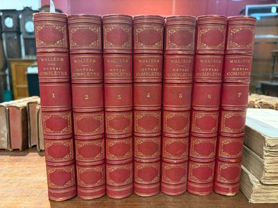 six livres rouges sont empilés les uns sur les autres sur une table
