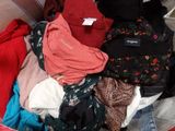 une valise pleine de vêtements, dont certains portent encore leur étiquette de prix