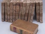 several old books stacked on top of each other on a white surface