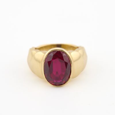 une bague en or avec une pierre rouge au centre