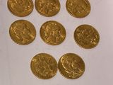 six gold sovereigns of various sizes and shapes on a white surface