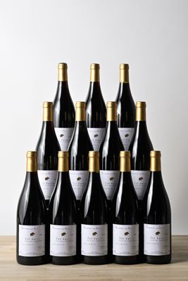 six bouteilles de vin sont posées sur une table devant un mur blanc