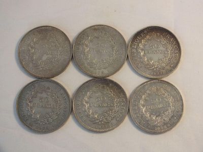 six silver coins sitting on top of each other on a white surface