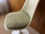 a white chair with a green cushion on it in the corner of a room