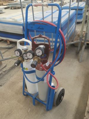 un chariot bleu sur lequel se trouvent un bidon d'essence et un manomètre