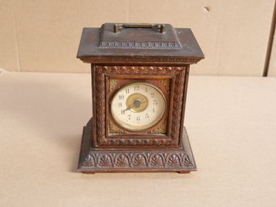 a small clock sitting on a table with a box in the background
