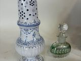 a white and blue vase sitting next to a green glass bottle