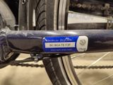 a close up of a bicycle chain with a blue tag attached to it