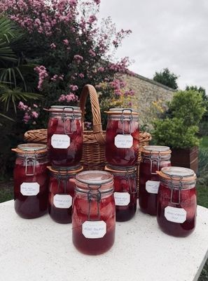 Plusieurs pots de confiture sont posés sur une table devant un panier de fleurs