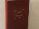 un livre rouge avec des lettres dorées posé sur une surface blanche