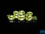 a bunch of green peridots on a black surface