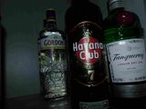 Des bouteilles d'alcool sont alignées sur une étagère dans une pièce sombre