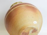 a brown vase sitting on a white surface with a tag on it