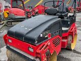 a red and black road roller sitting on top of a parking lot