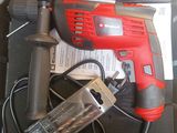 a red drill in a case with a corded cord