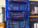 une pile de caisses bleues et une cafetière posées par terre