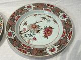 two plates with flowers and birds on them on a table