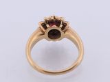 a close up of a gold ring with a red stone