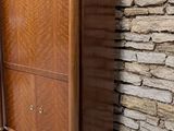 a tall wooden cabinet sitting against a stone wall