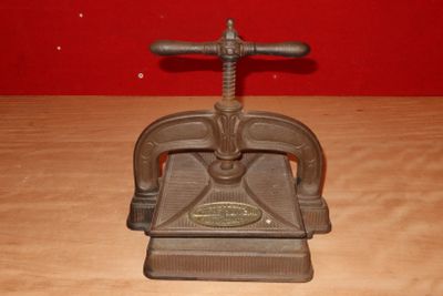 an old cast iron press sits on a wooden table