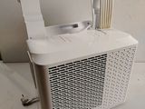 a white air conditioner sitting on the floor next to a wall
