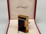 une image représentant un briquet doré dans une boîte rouge ornée d'une bande noire et rouge