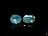 two pieces of blue topazte sit on a black surface