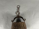 un petit récipient en métal suspendu à un crochet fixé au mur