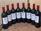 six bottles of red wine are lined up on a wooden table