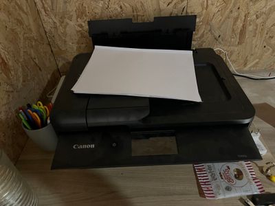 une imprimante posée sur un bureau, à côté d'une pile de papiers