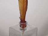 a small glass vase with a feather on top of it