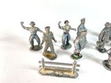 several figurines of men with hats, tails, and a bench