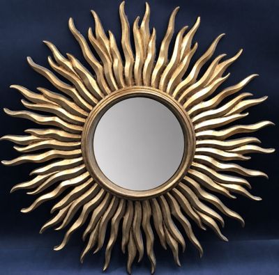 a gold sun shaped mirror sitting on top of a blue wall