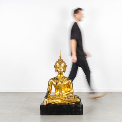 a man walking past a golden buddha statue in a room