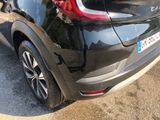the rear end of a black car parked on the side of the road