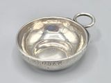 an antique silver bowl with a handle on a white surface